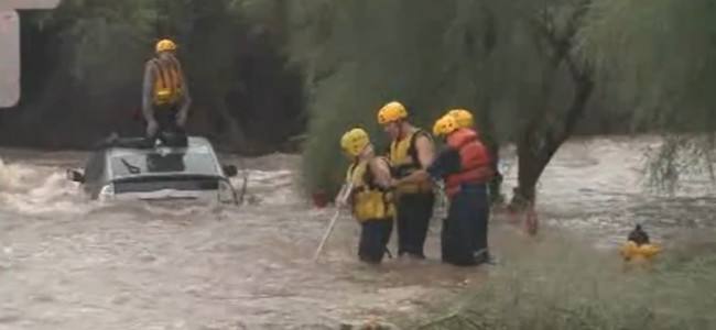 Firefighters rescue a driver trapped in a flooded wash